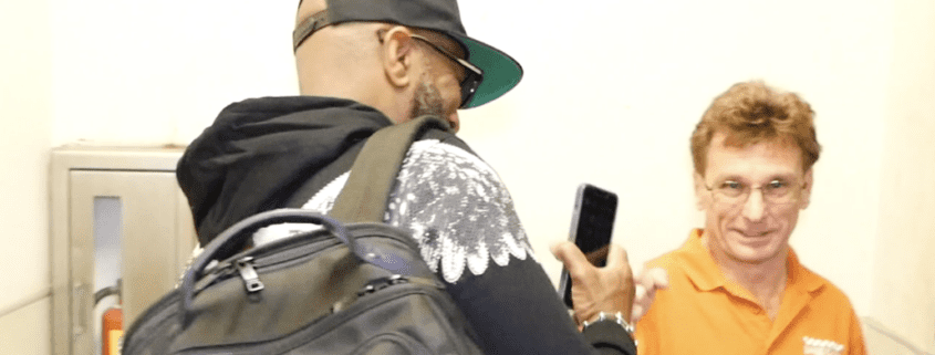 Man with backpack and phone, another smiling.